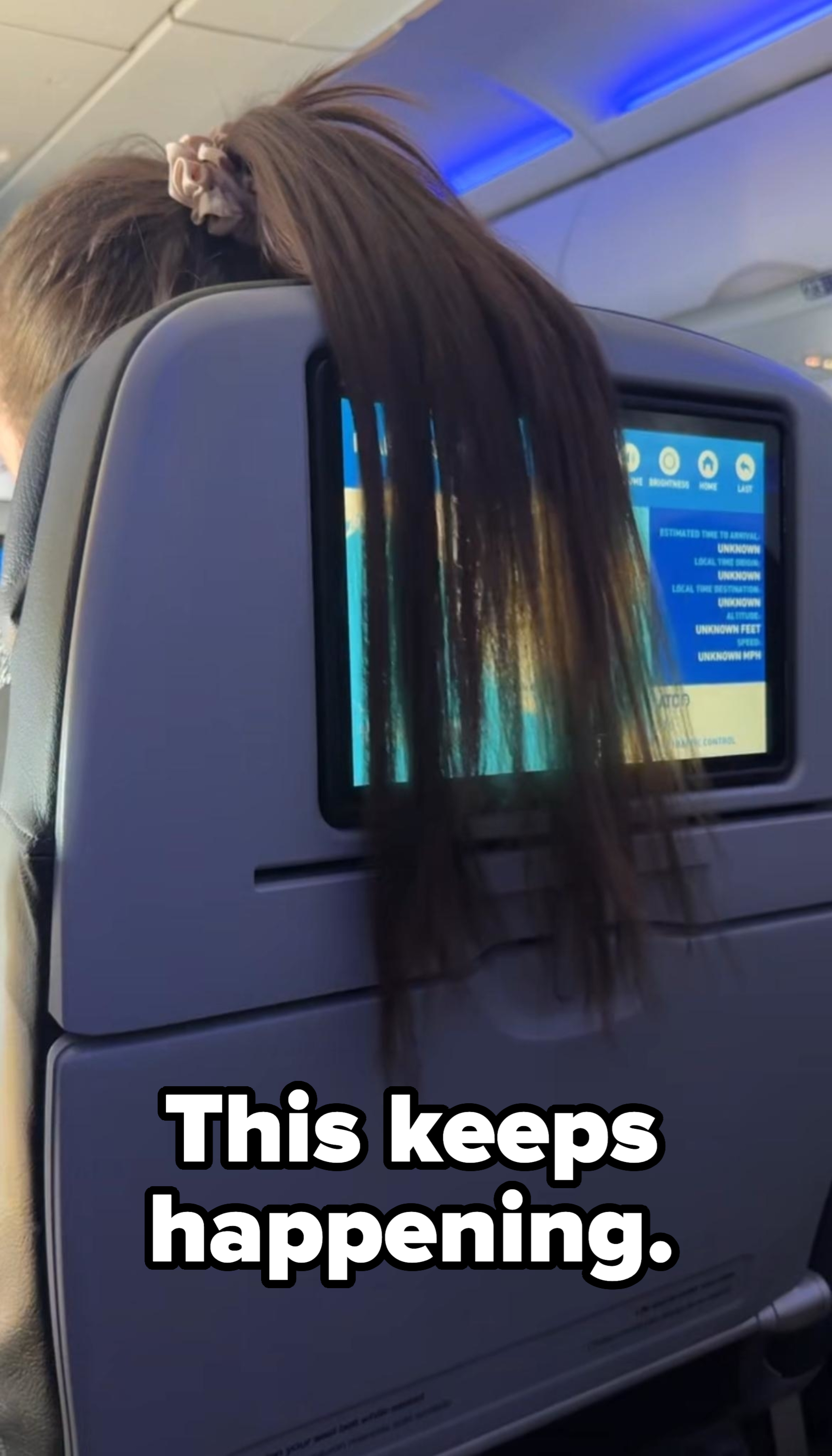 Person&#x27;s hair draped over an airplane seatback screen, covering the display