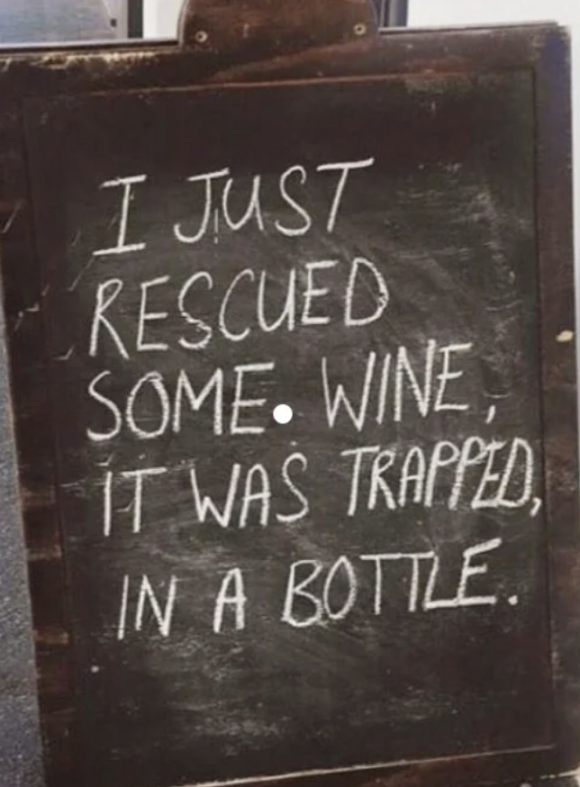 Chalkboard sign reads: &quot;I just rescued some wine, it was trapped, in a bottle.&quot;