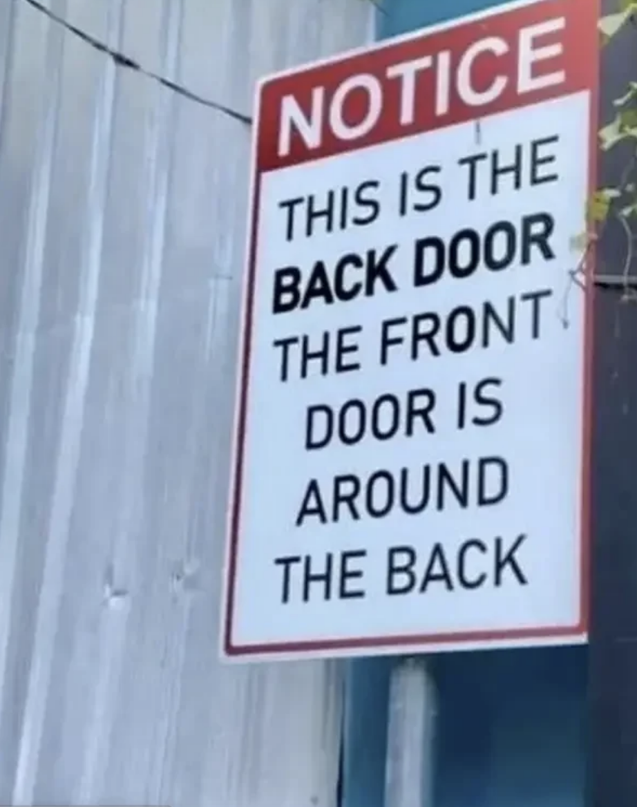 Sign reads: &quot;NOTICE. This is the back door. The front door is around the back.&quot;