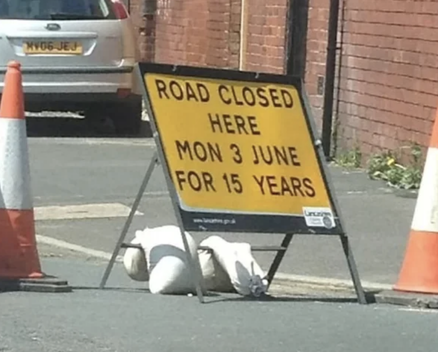 Road closed sign stating closure from Monday, June 3, for 15 years, surrounded by traffic cones