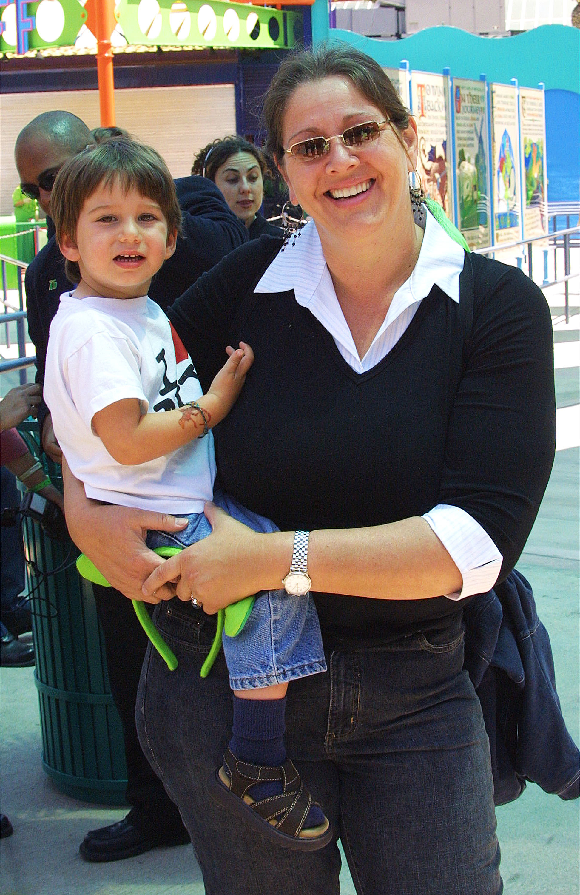 A woman holding a young child, both smiling, standing outdoors