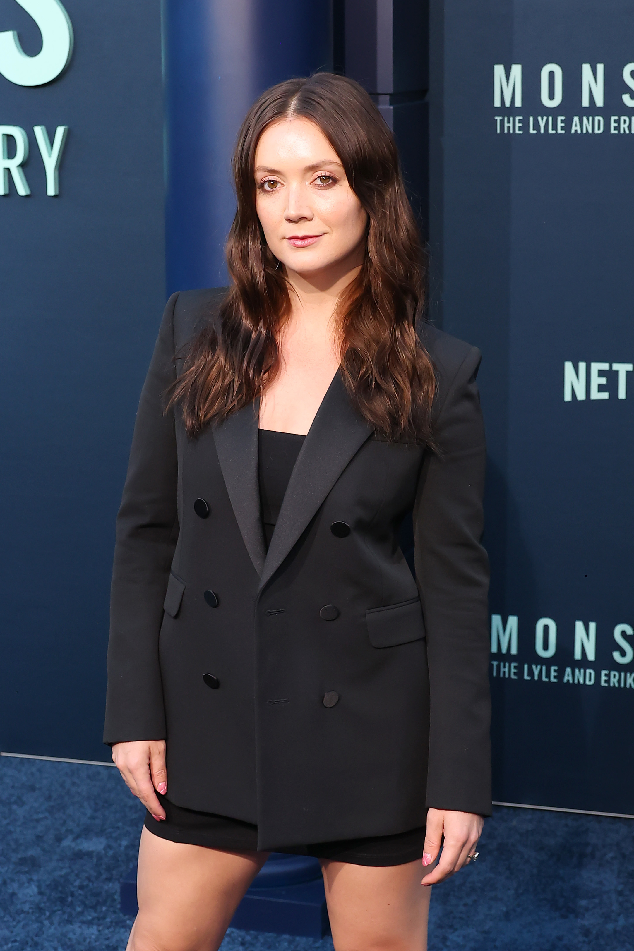 I don&#x27;t know who this person is. A woman on the red carpet wears a black double-breasted blazer over a fitted black dress at a Netflix event