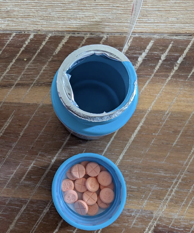 Open bottle of vitamin tablets on a wooden surface with lid showing tablets inside