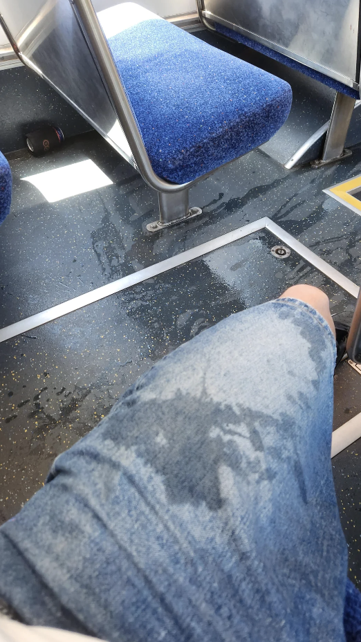 Wet jeans on a bus seat, with water spill visible on the floor