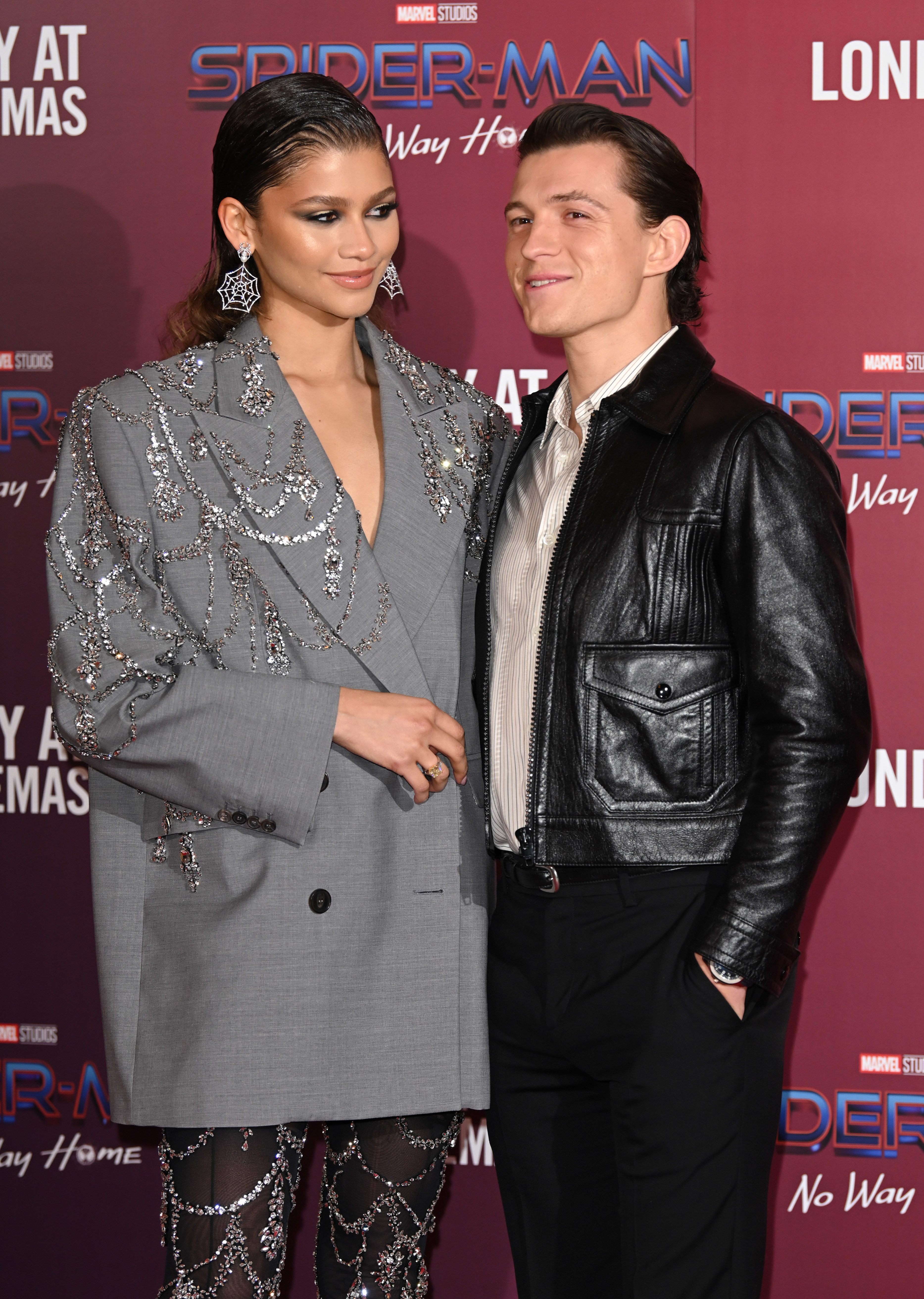 Zendaya in a bejeweled blazer and sheer leggings and Tom Holland in a leather jacket and pants on the red carpet