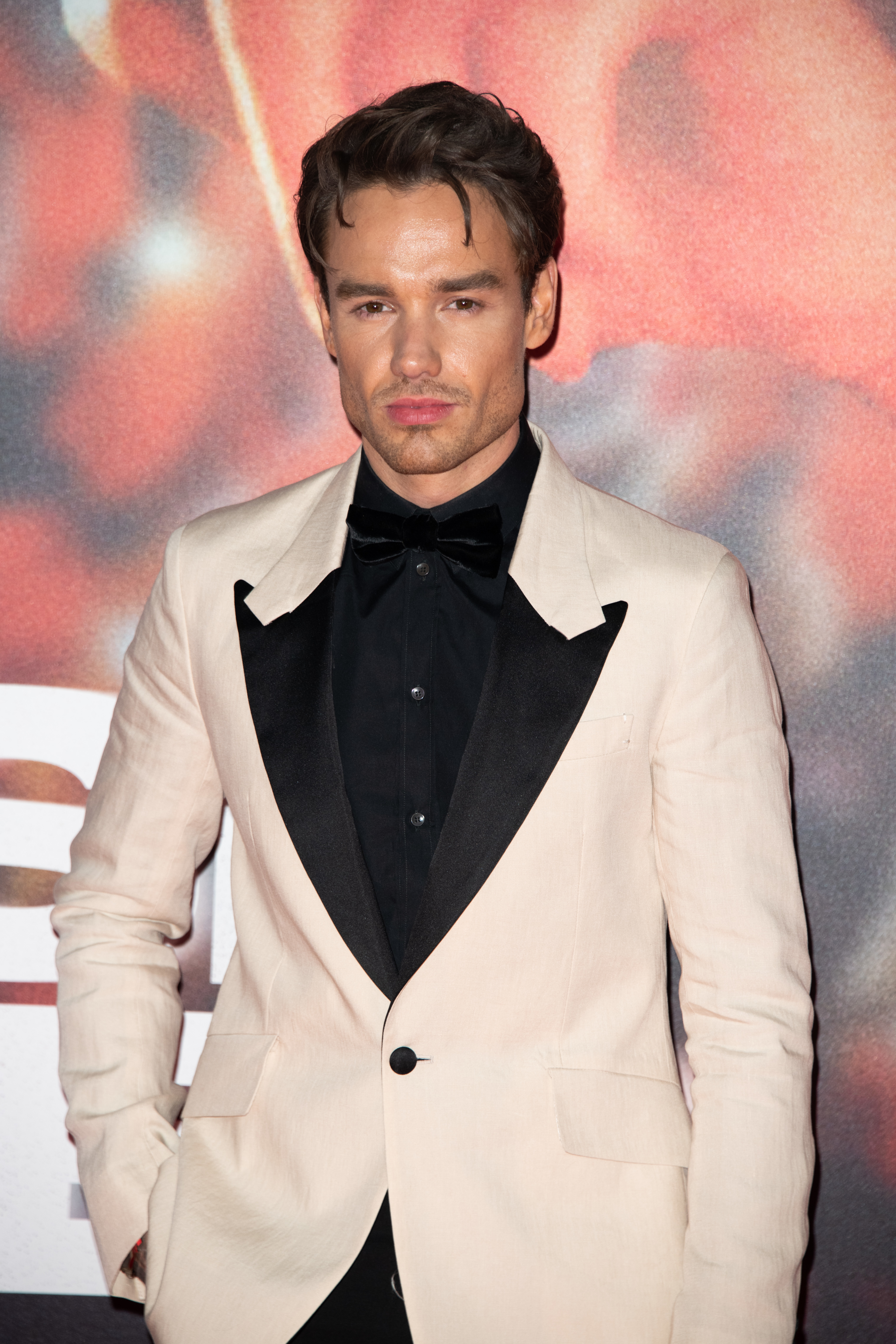 I don’t know who this person is. A man in a tuxedo with a light jacket poses on the red carpet