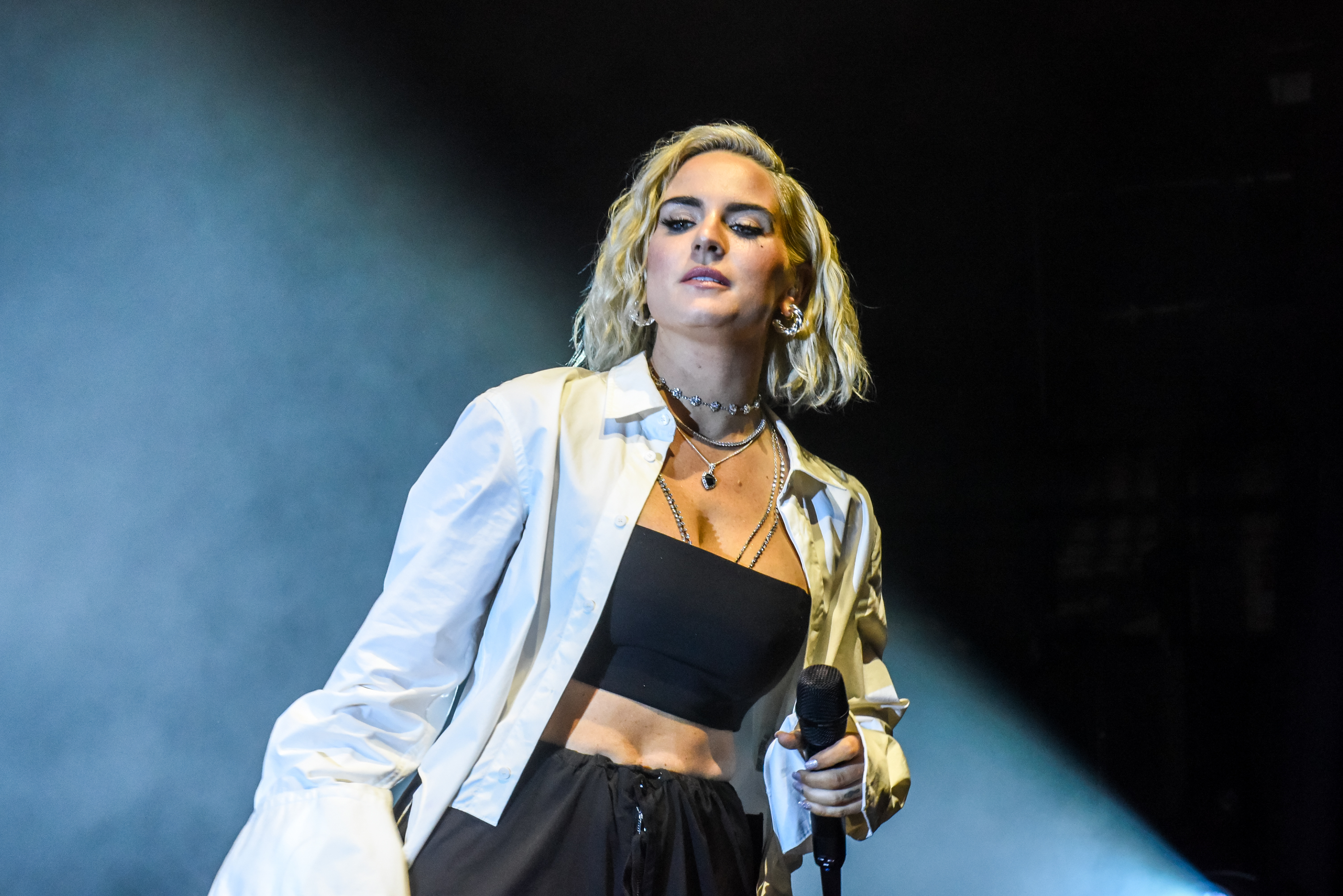 JoJo performs onstage in a bandeau top with pants and a button top with layered necklaces