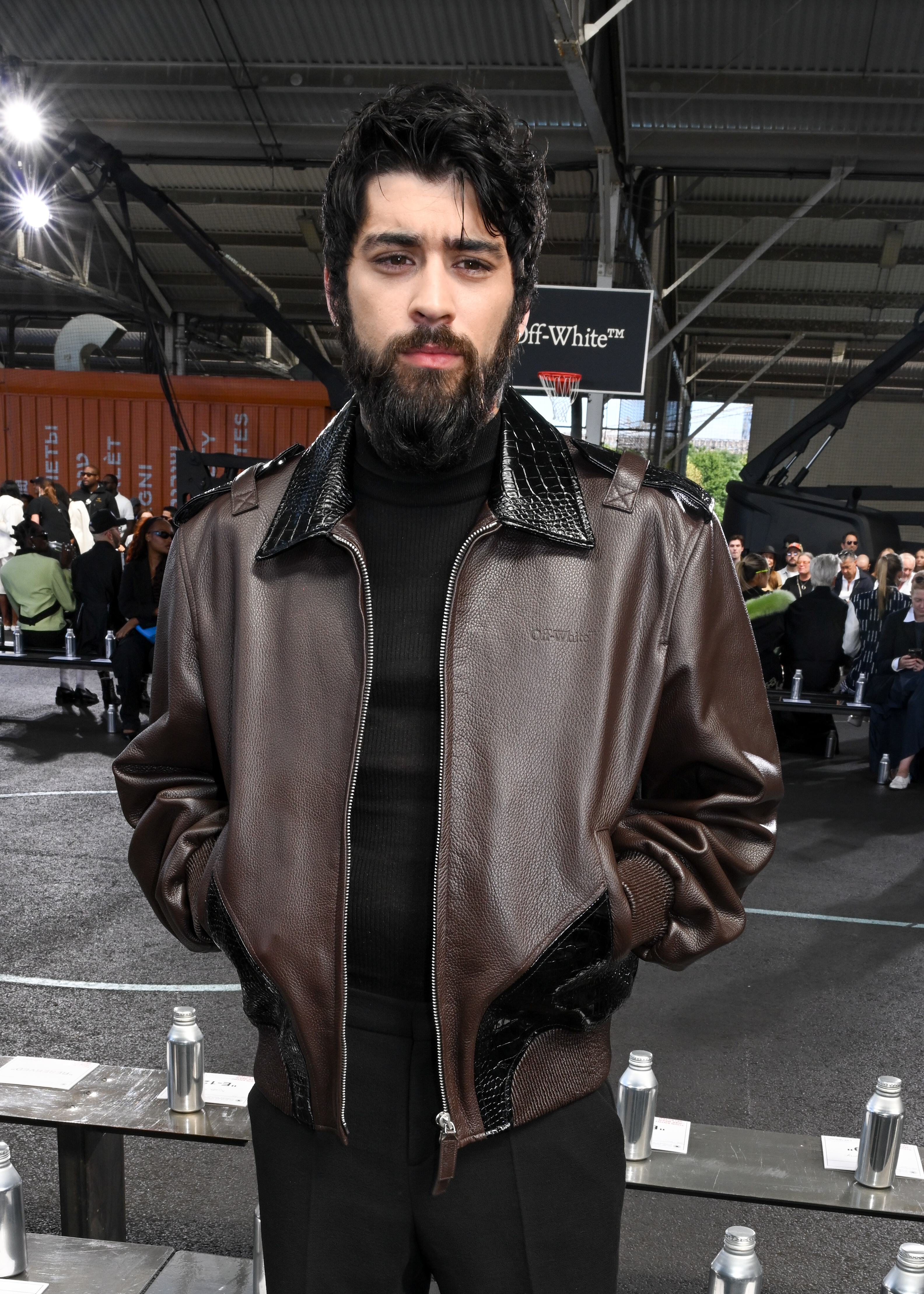 Man in a leather jacket with hands in pockets at a fashion event. Unknown identity