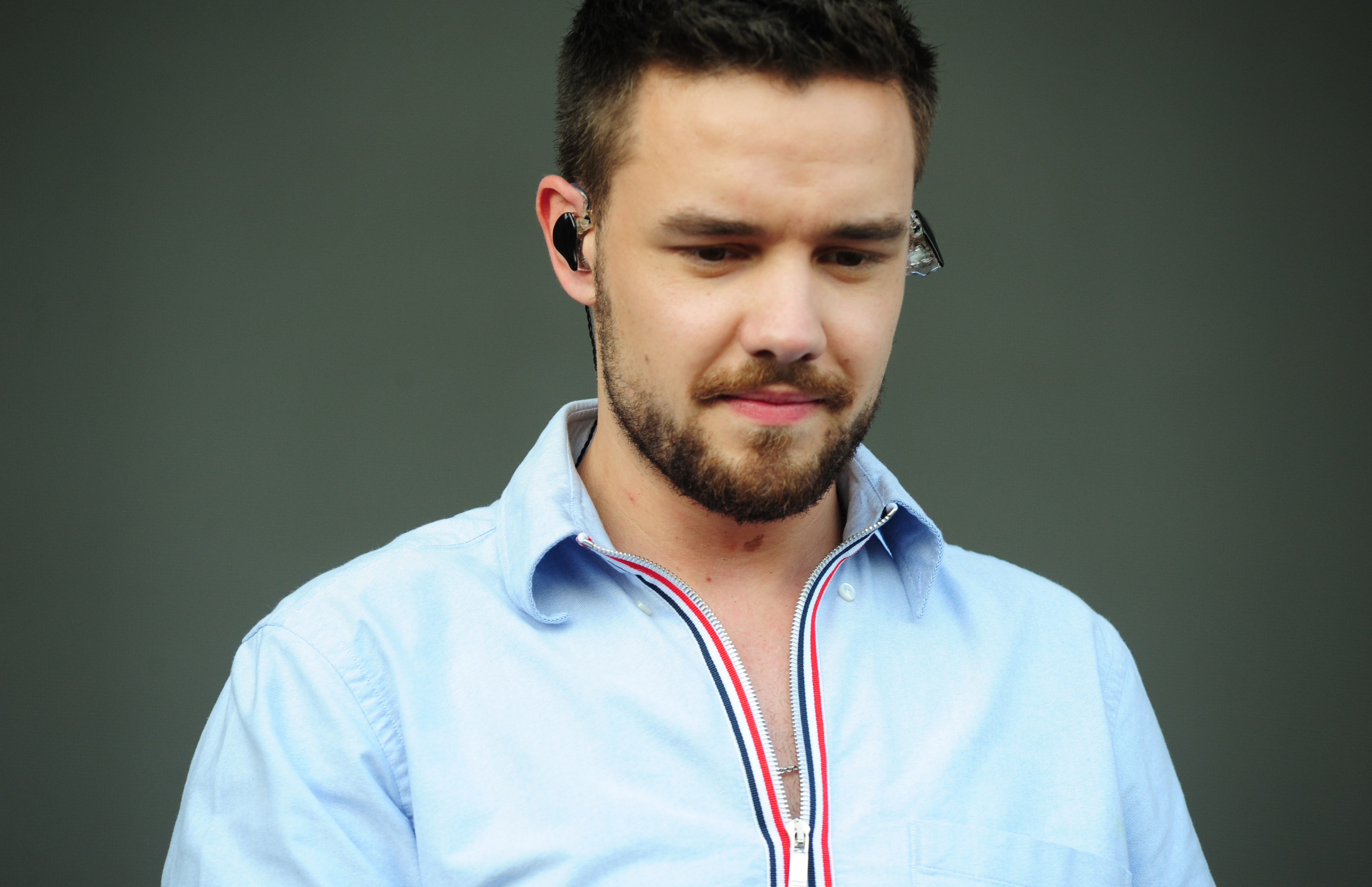 A person wearing a button-up shirt stands against a plain background