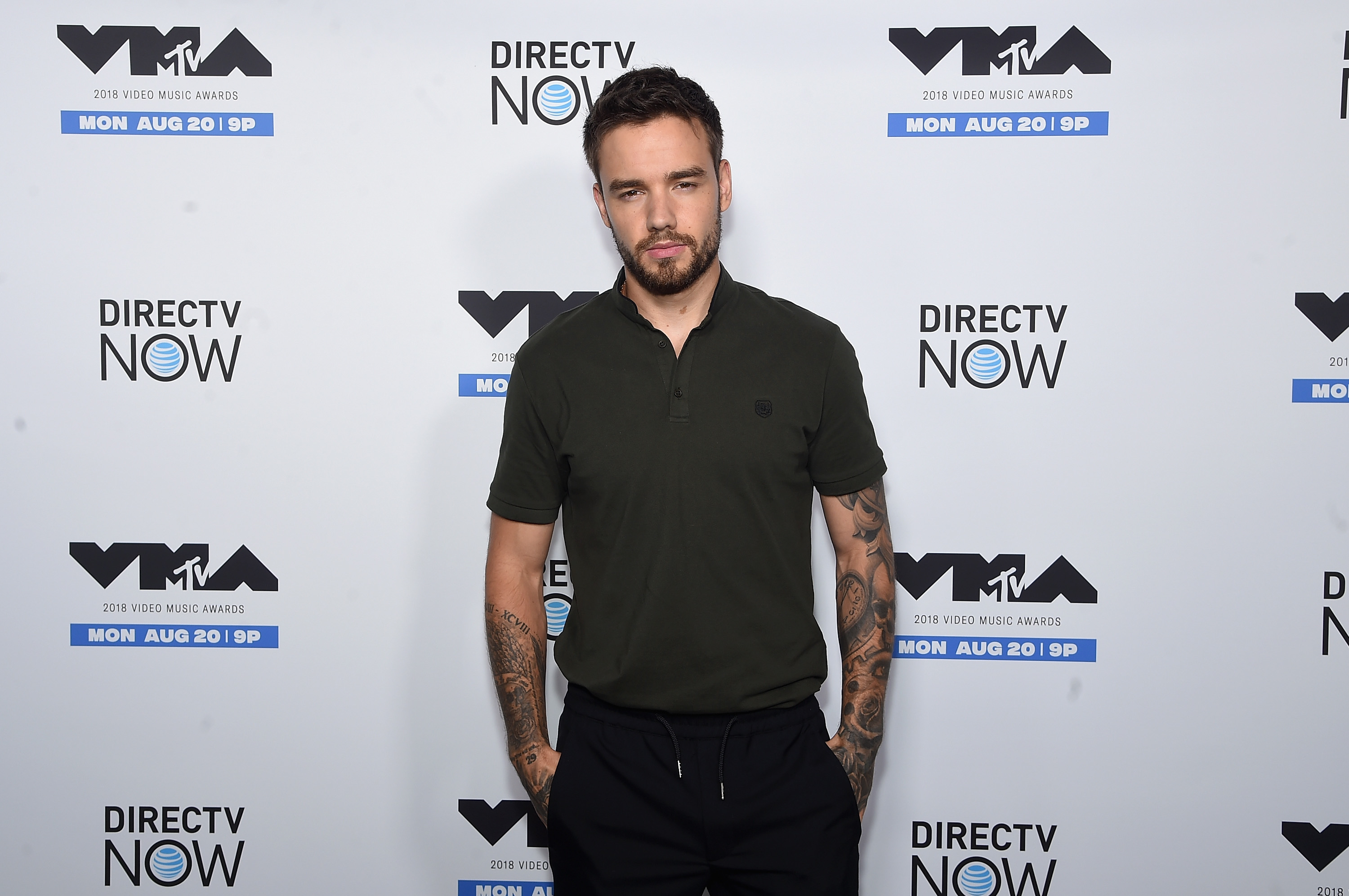 A man in casual attire stands in front of a wall with MTV and DirecTV logos