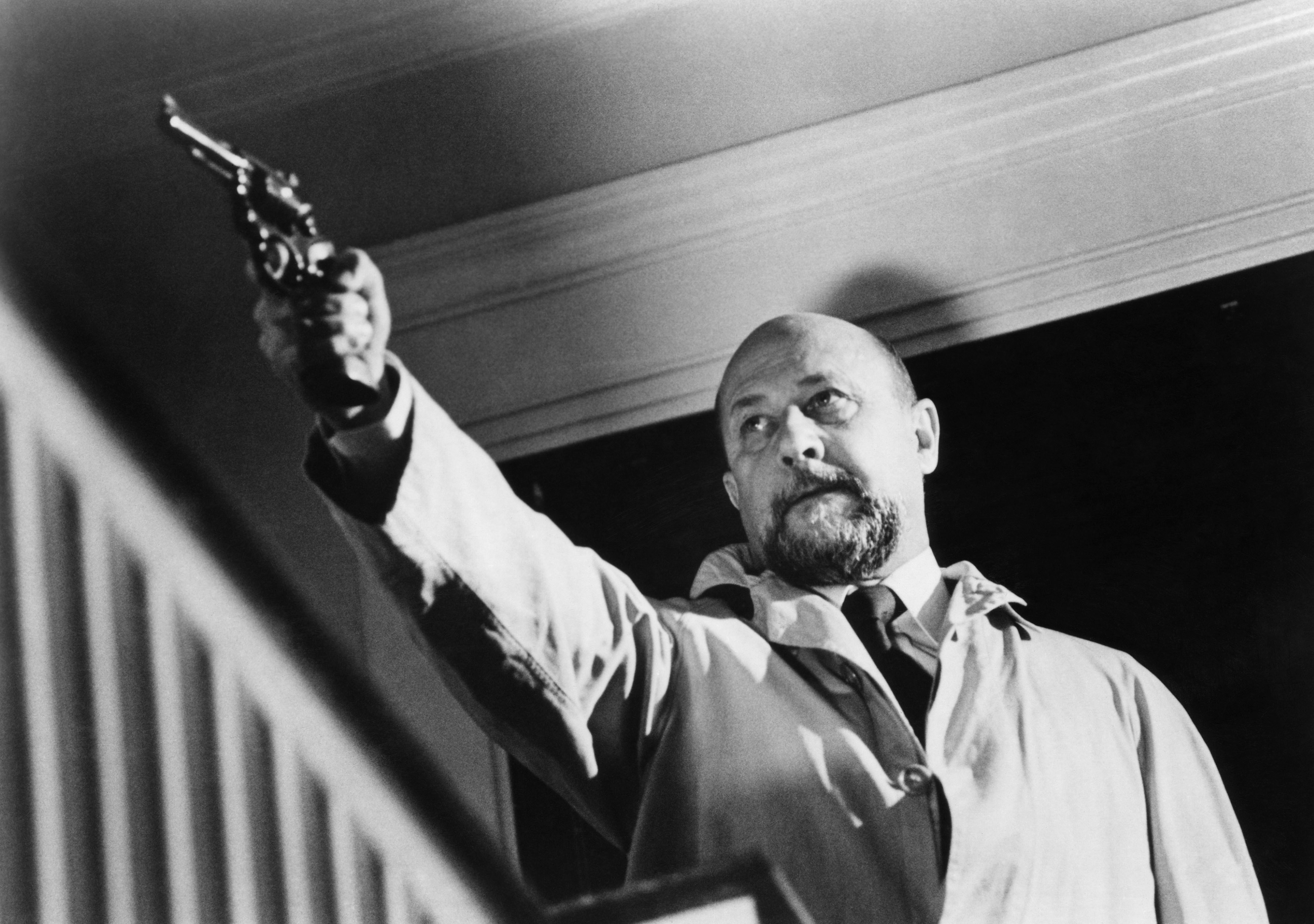 Donald Pleasance wearing a trench coat while pointing a gun in "Halloween"