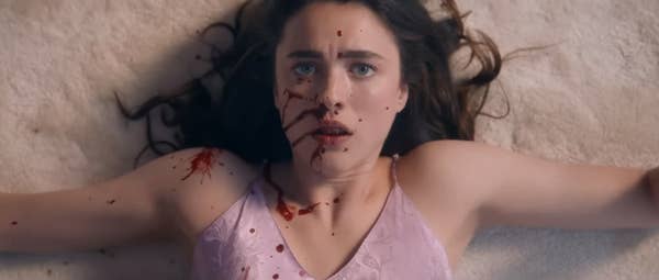 Close-up of a woman, played by Kathryn Newton, lying on the ground with blood splattered on her face, wearing a sleeveless top. Scene from a dramatic TV or movie moment