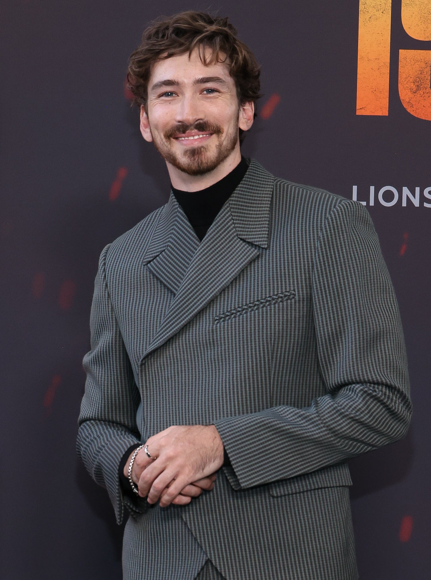 Dylan Arnold in a pinstripe suit on the red carpet for the "1992" premiere