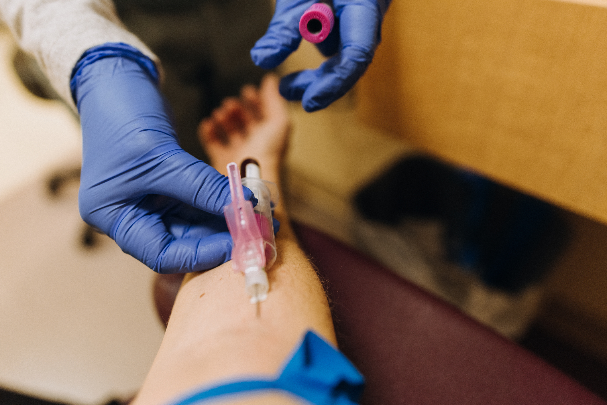 Medical professional drawing blood from a person&#x27;s arm using a needle and syringe