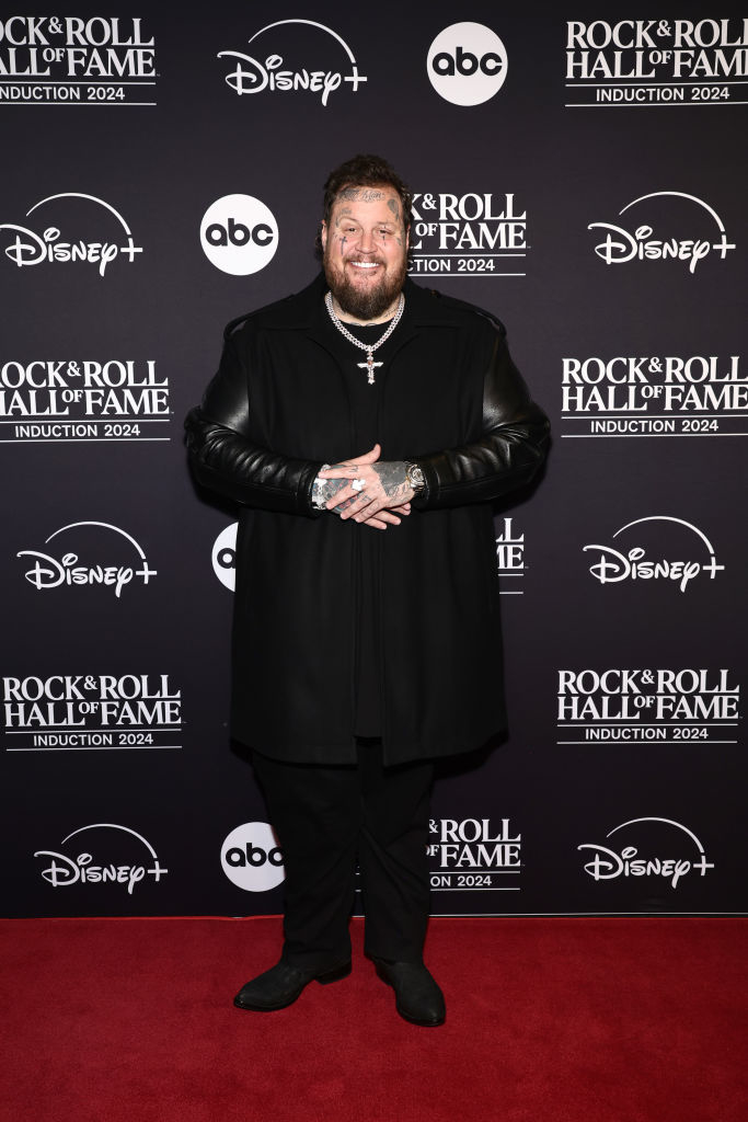 Person in black coat smiling on Rock &amp;amp; Roll Hall of Fame red carpet backdrop