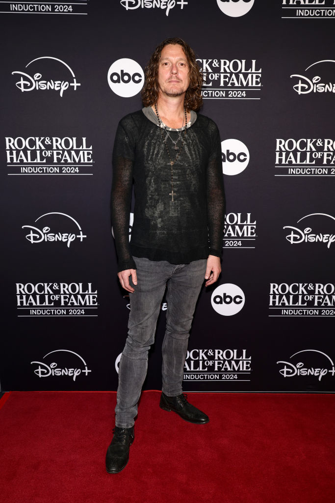 I don&#x27;t know who this person is. They are on a red carpet wearing a black sheer top and gray jeans at a Rock &amp;amp; Roll Hall of Fame event