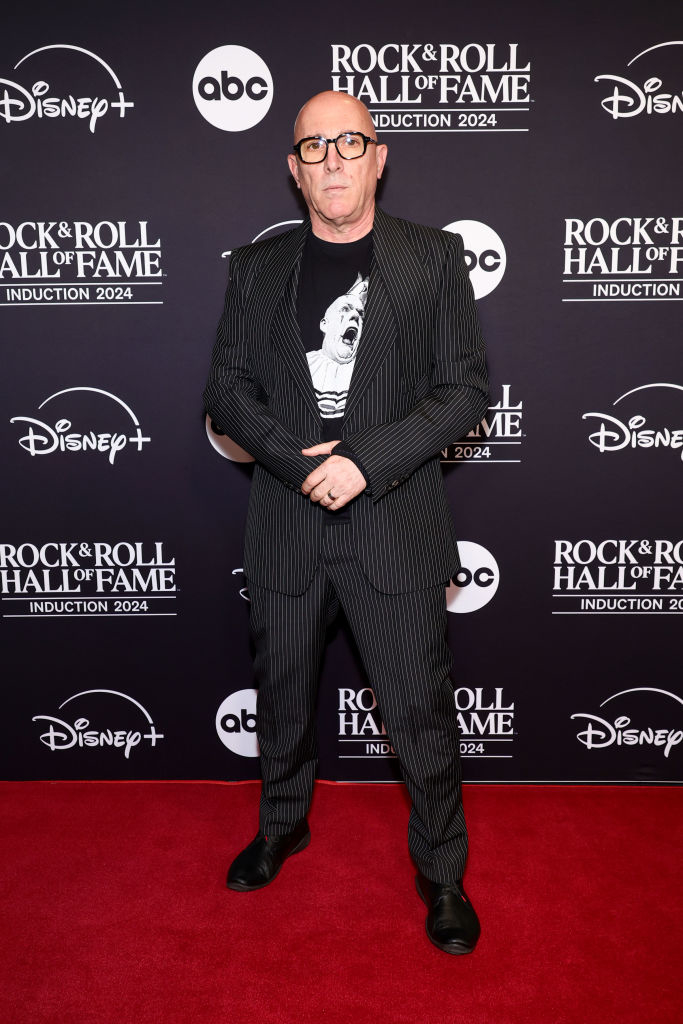 A person on the red carpet for the Rock &amp;amp; Roll Hall of Fame Induction 2024. They are wearing a pinstripe suit and graphic t-shirt