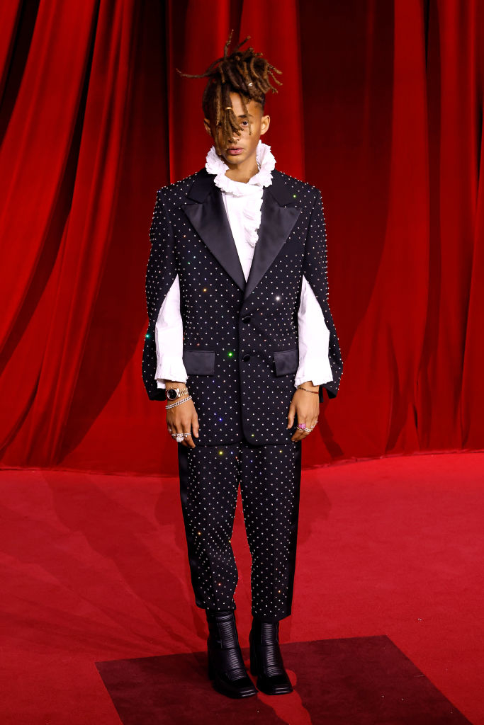 Person in a dotted suit with ruffled shirt on a red carpet