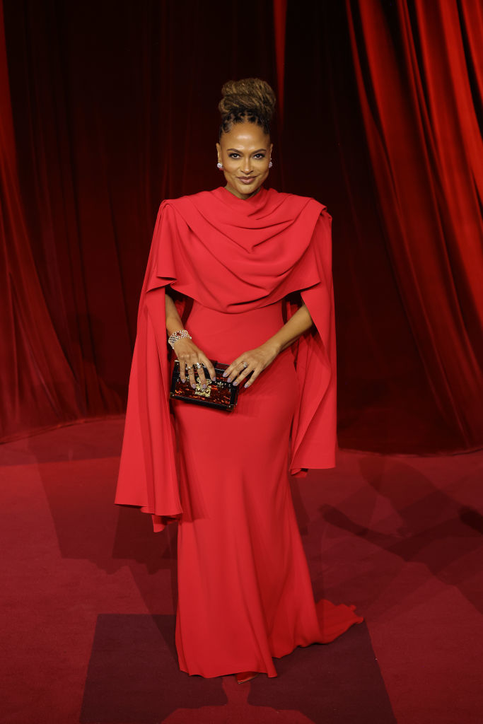 I don&#x27;t know who this is. The person is on a red carpet wearing an elegant, long gown with draped fabric and holding a clutch