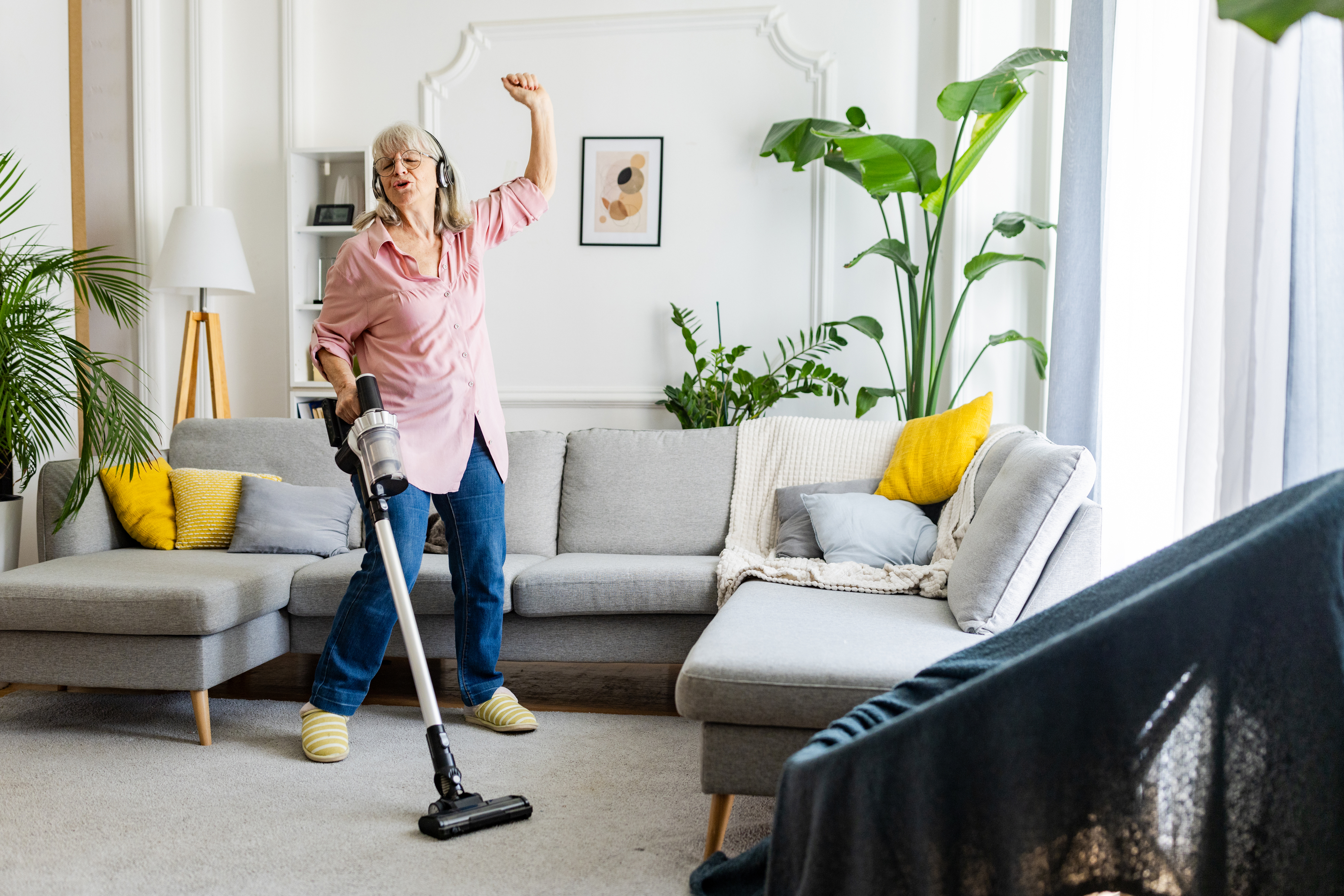 Older adult vacuuming living room and dancing around