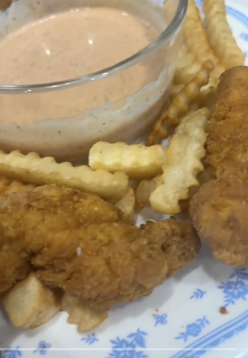 Plate of crinkle-cut fries, crispy chicken tenders, and a bowl of dipping sauce