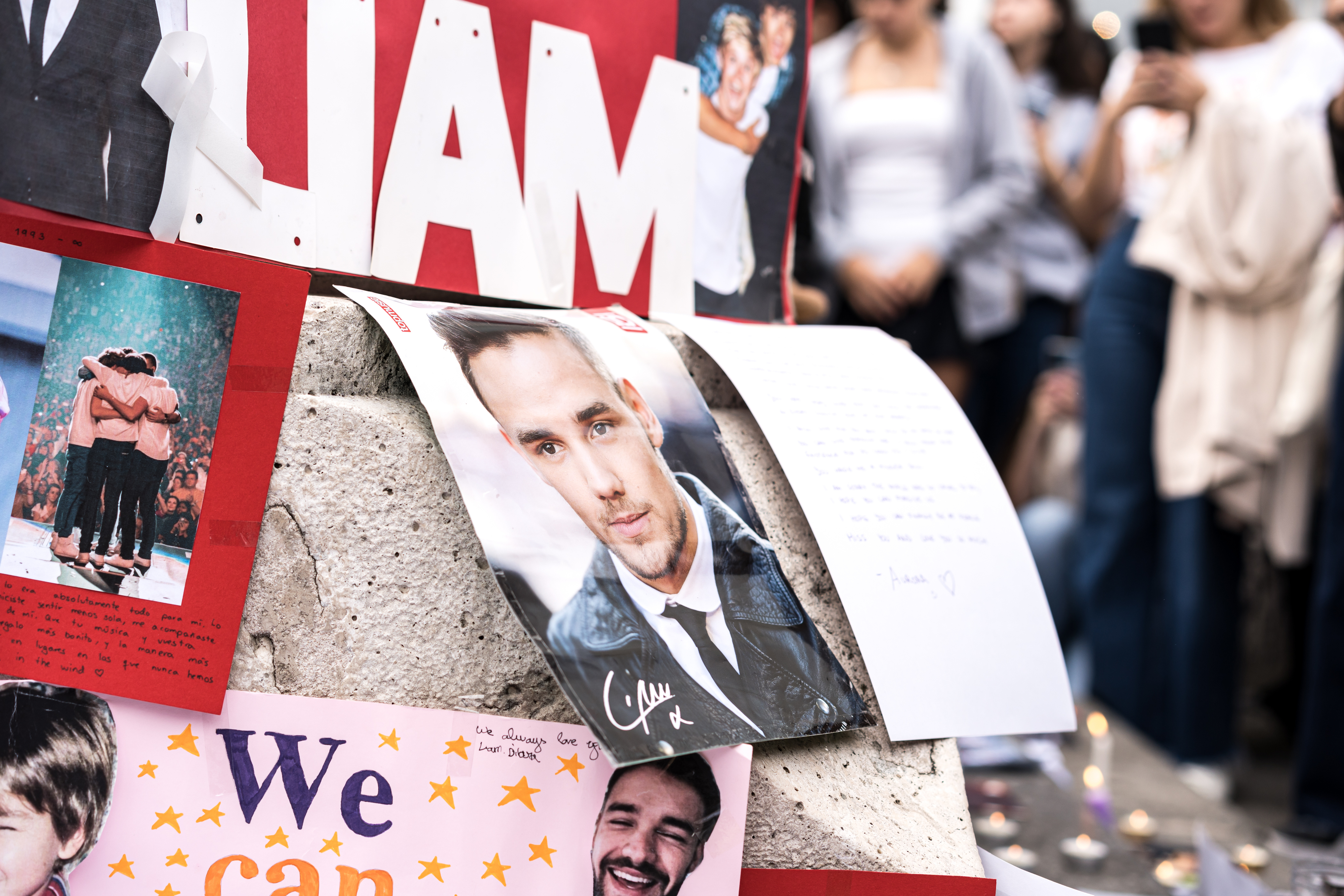 People gathered around a memorial with photos and messages for a man