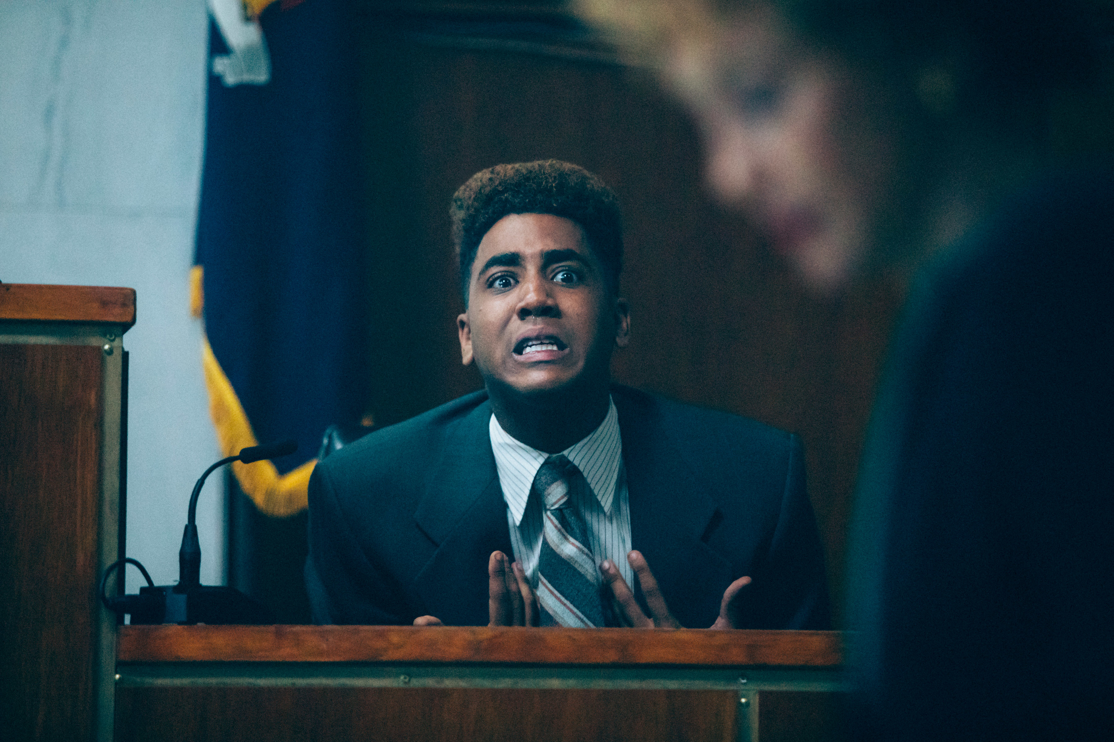 Person in court scene, dressed in a suit and tie, expressing intense emotion while testifying