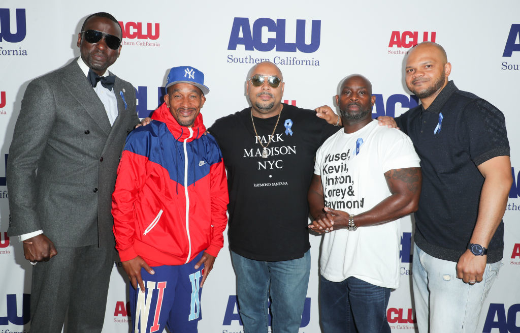 Five individuals pose at an ACLU event. They wear a mix of casual and formal clothing