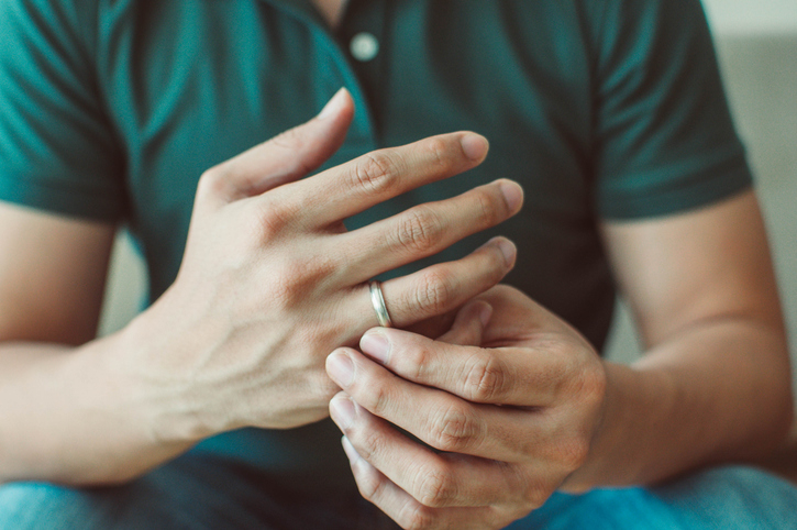 Person adjusts their wedding ring, wearing a polo shirt