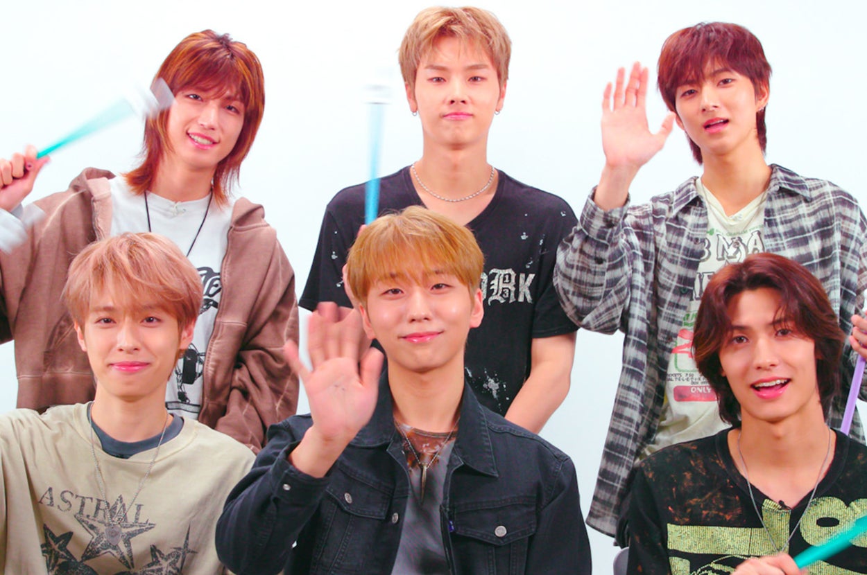 Six individuals, wearing casual outfits, holding sticks in various colors, and posing in front of a white background with a BuzzFeed Celeb logo. Names unknown