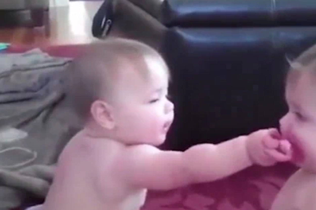 Two babies interacting playfully indoors