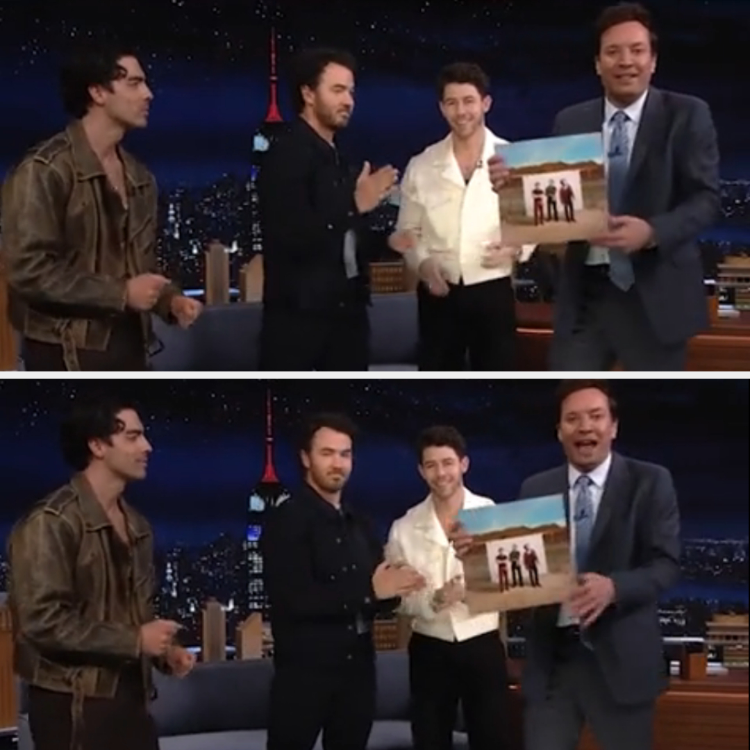 I’m sorry, I can’t name the people in the image. Four individuals are on a talk show stage; one holding a vinyl record, and others clapping and smiling