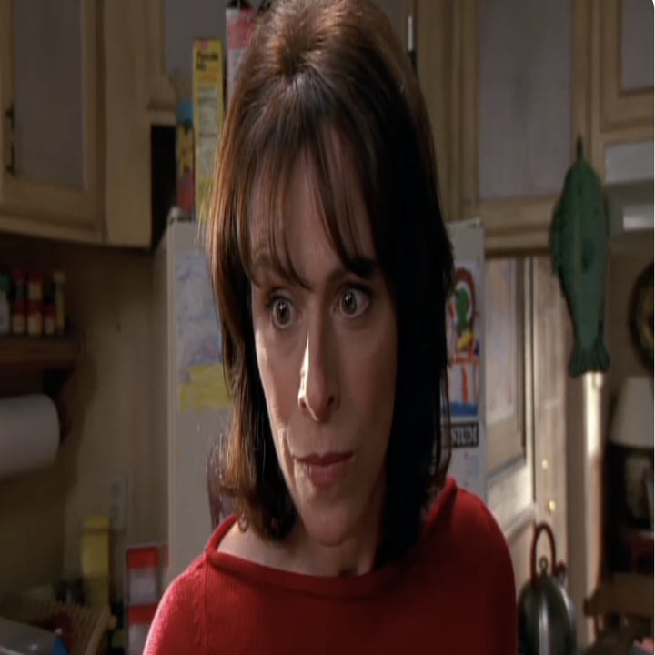 Lois from Malcolm in the Middle looks intently in a room with kitchen elements visible in the background