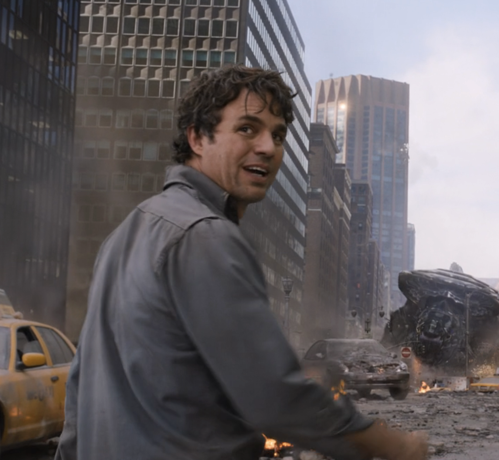 Mark stands on a city street with debris and a taxi nearby, looking back