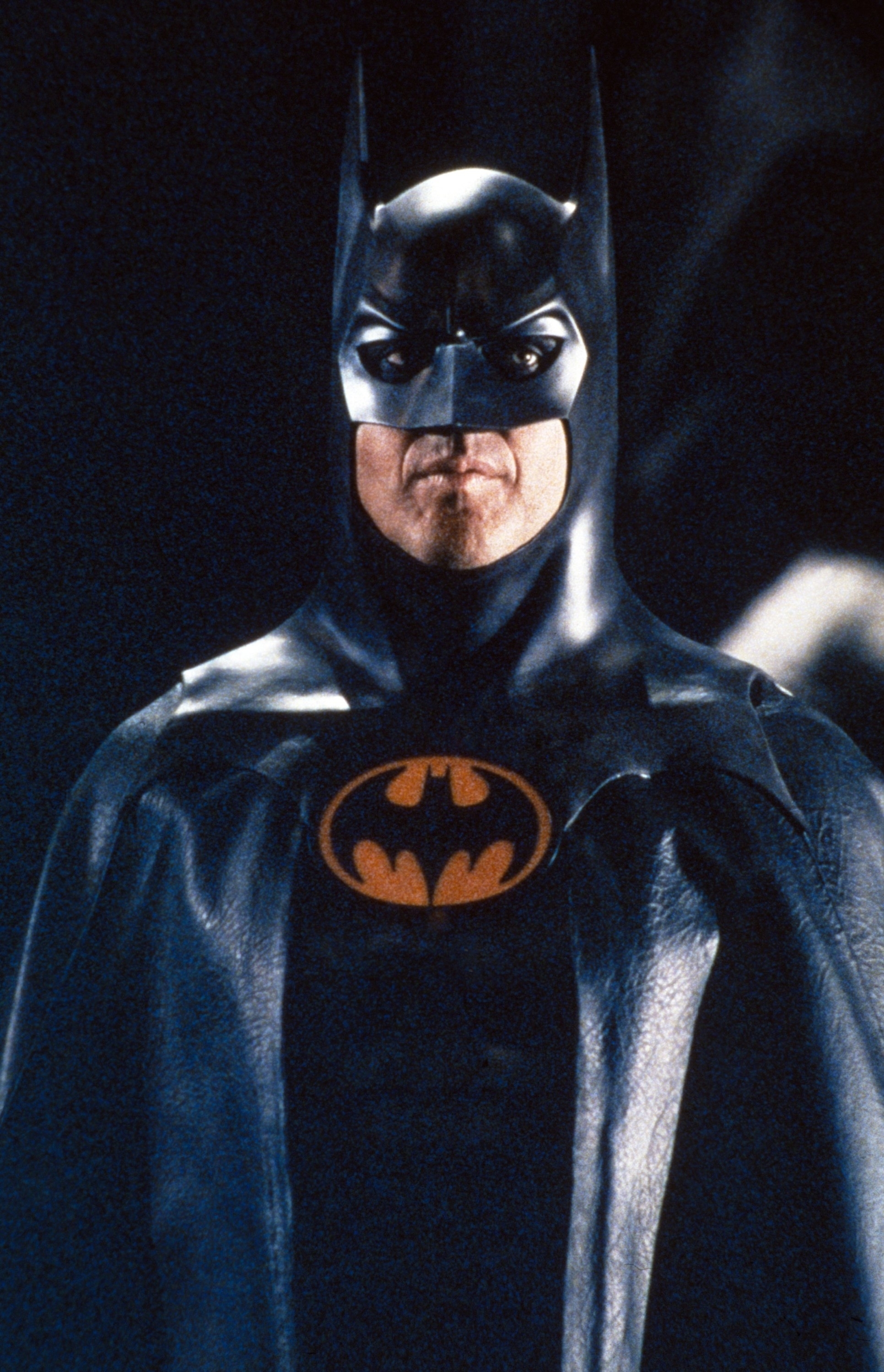 Batman in classic costume with iconic logo on chest, standing with serious expression