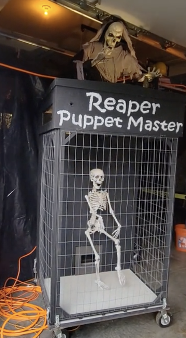 Halloween display showing a skeletal Reaper Puppet Master with a skeleton in a wire cage