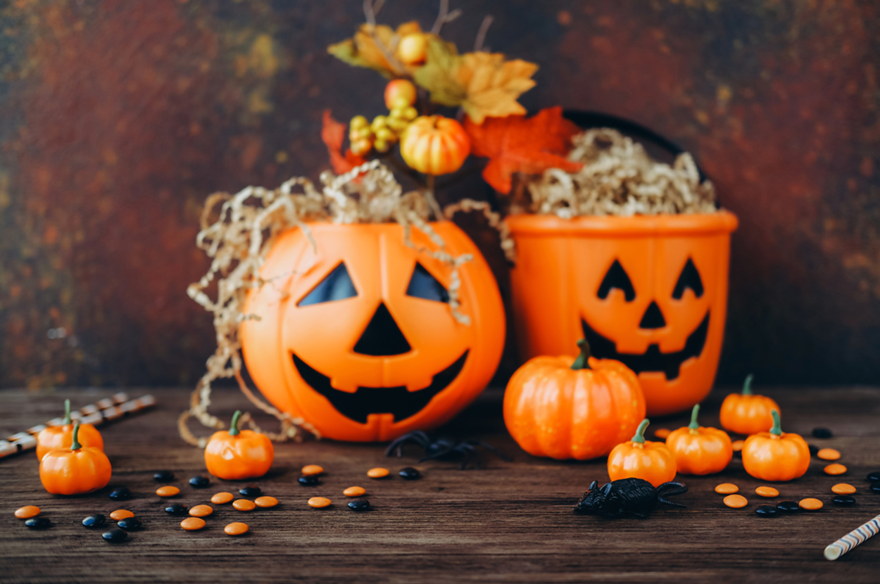 Halloween-themed arrangement with carved pumpkin decorations, small pumpkins, and candy on a wooden table