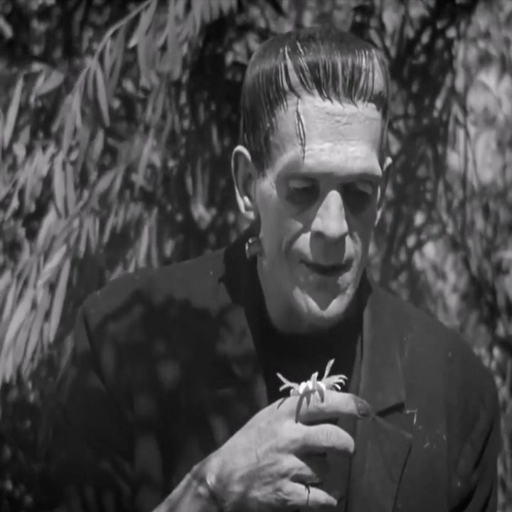Frankenstein's monster holds a flower, wearing a suit with neck bolts, in a film scene