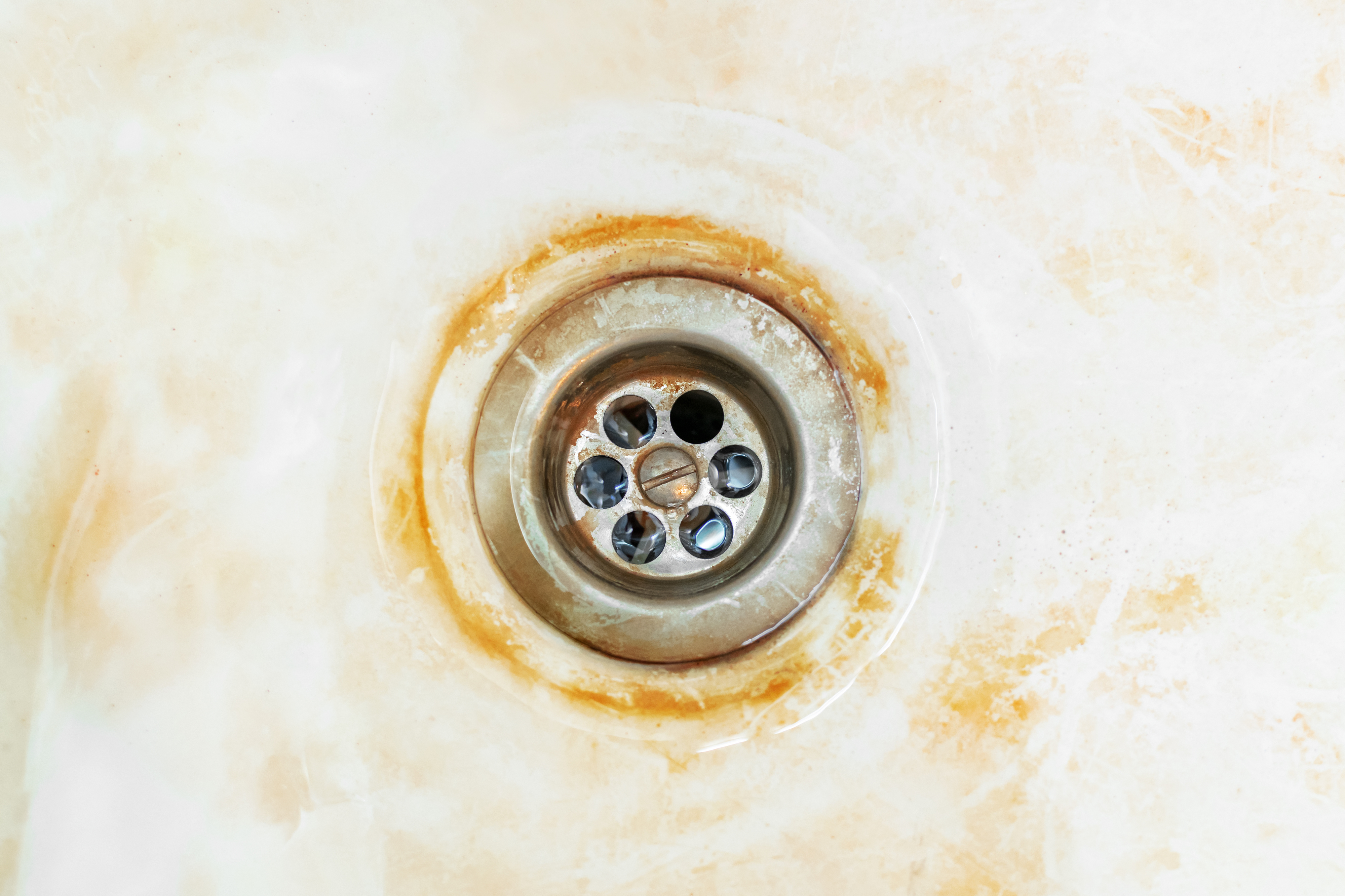 Close-up of a rusty, stained sink drain