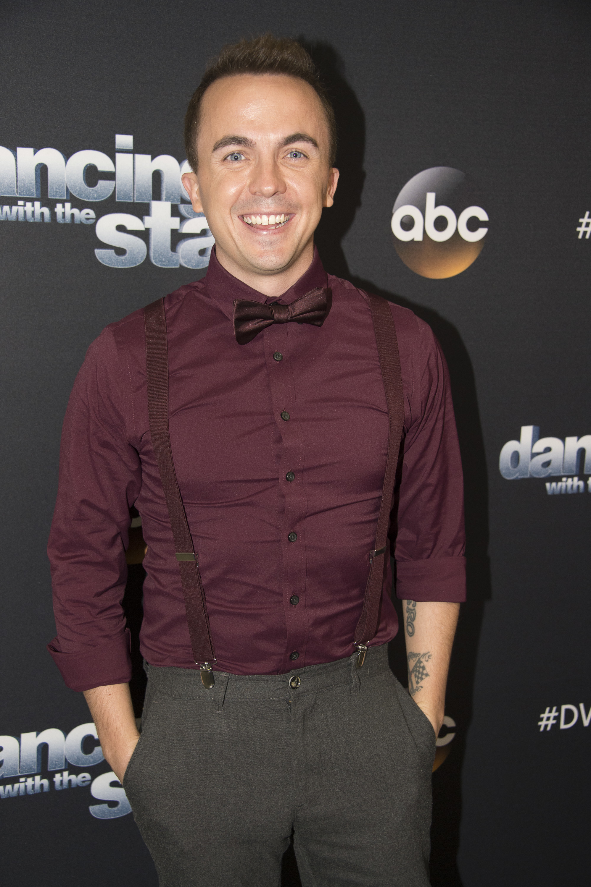 Man in maroon shirt with bow tie and suspenders on &quot;Dancing with the Stars&quot; event backdrop