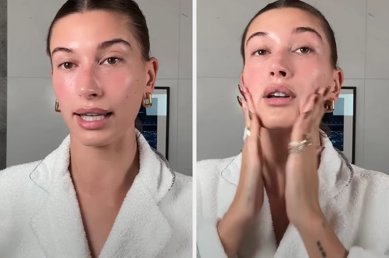 Hailey Bieber in a white robe applies skincare, focusing on her face, showcasing a natural beauty routine