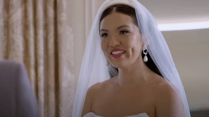 Taylor from Love Is Blind wearing a strapless gown and veil smiles during a wedding ceremony scene