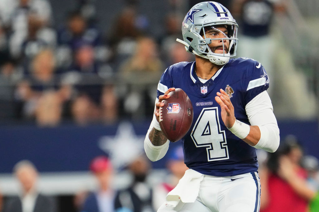 A football player in a Dallas Cowboys uniform, wearing number 4, prepares to throw a pass during a game