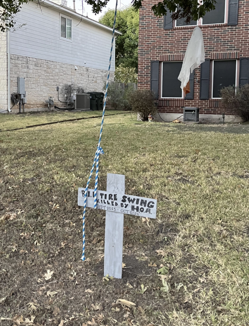 Wooden transverse  reads "R.I.P. Tire Swing, Killed by H.O.A, Sept 2023." Nearby is an bare  swing, indicating it was removed by a homeowners association
