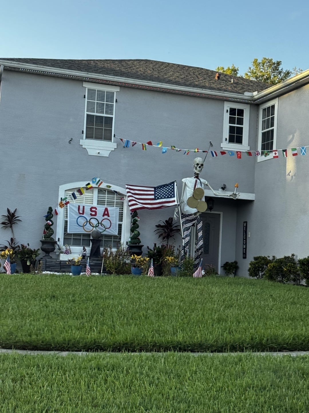 Skeleton decor holding cymbals successful  beforehand   of a location   with planetary   flags, a "USA" sign, and Olympic rings arsenic  portion  of the decorations