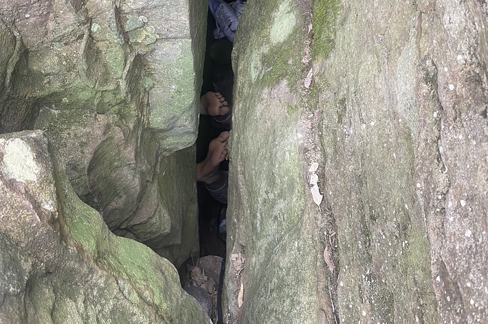 岩の隙間に人が挟まっている様子。両足が見える。