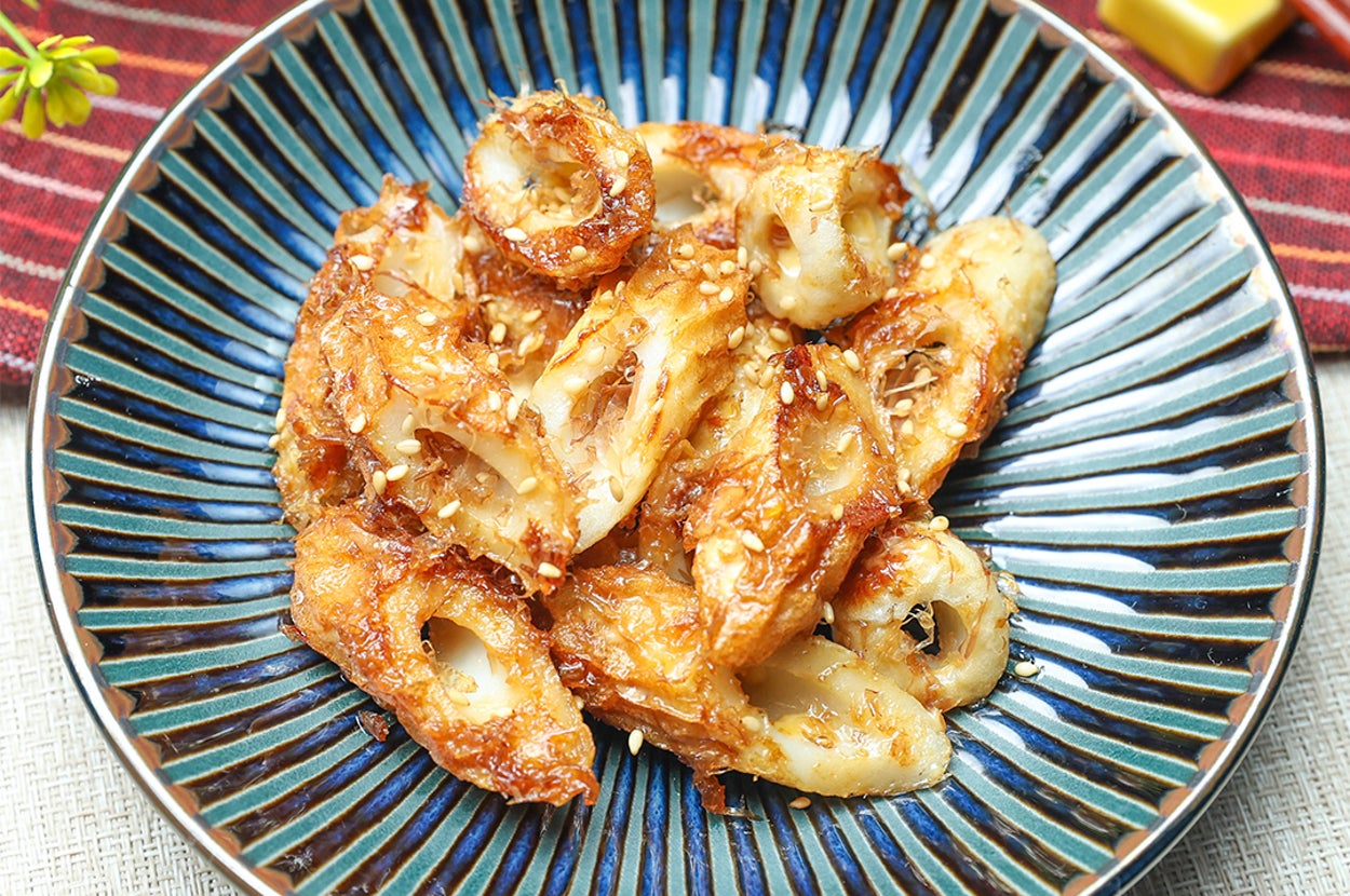 皿に盛られたごまがまぶされた焼きちくわの料理。葉の装飾が背景にある。