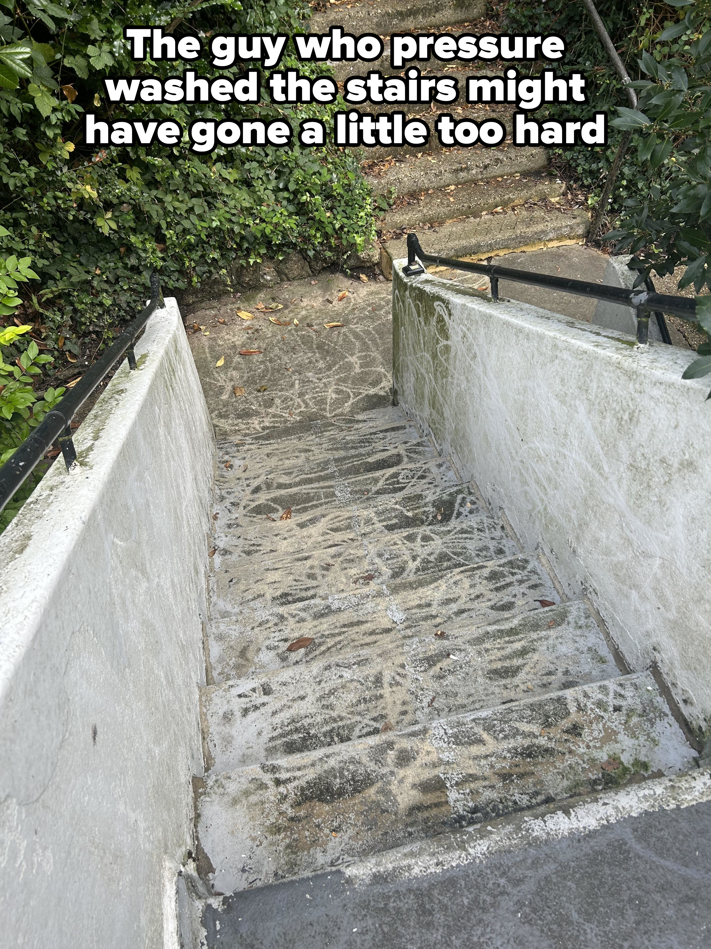 Outdoor stone staircase with metal railings, surrounded by greenery, leading upward and slightly curved