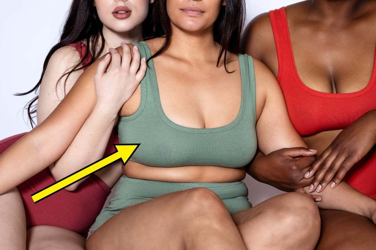 Three women in neutral-toned athletic wear sit close together, symbolizing body positivity and inclusivity