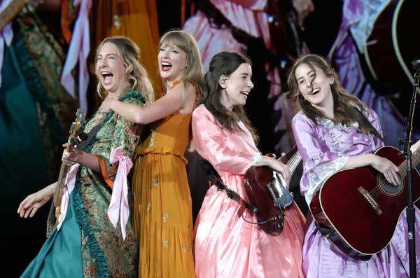 They appear to be performing on stage with musical instruments, wearing elegant dresses